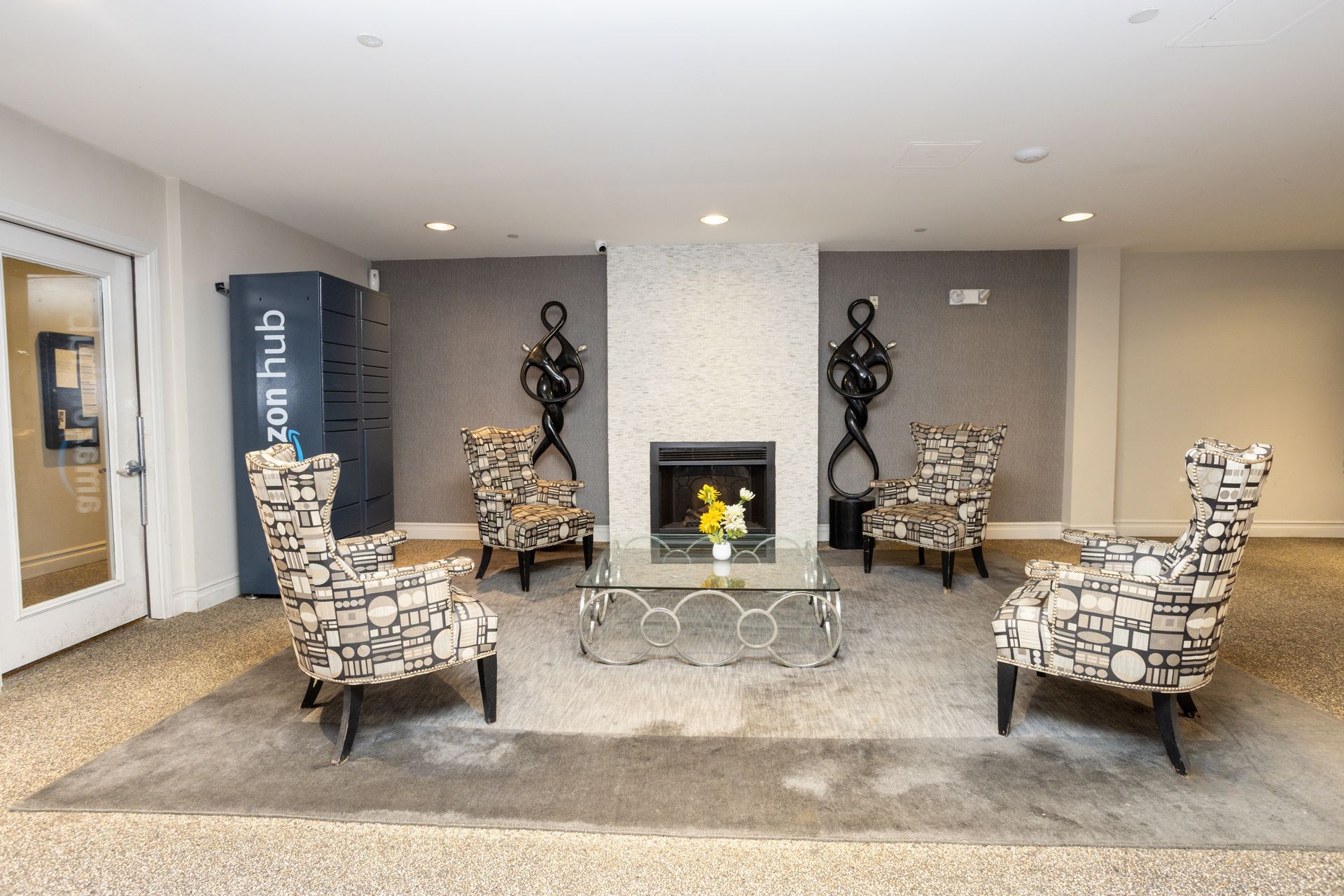 Modern lobby seating area with patterned armchairs, glass tables, and a fireplace centerpiece