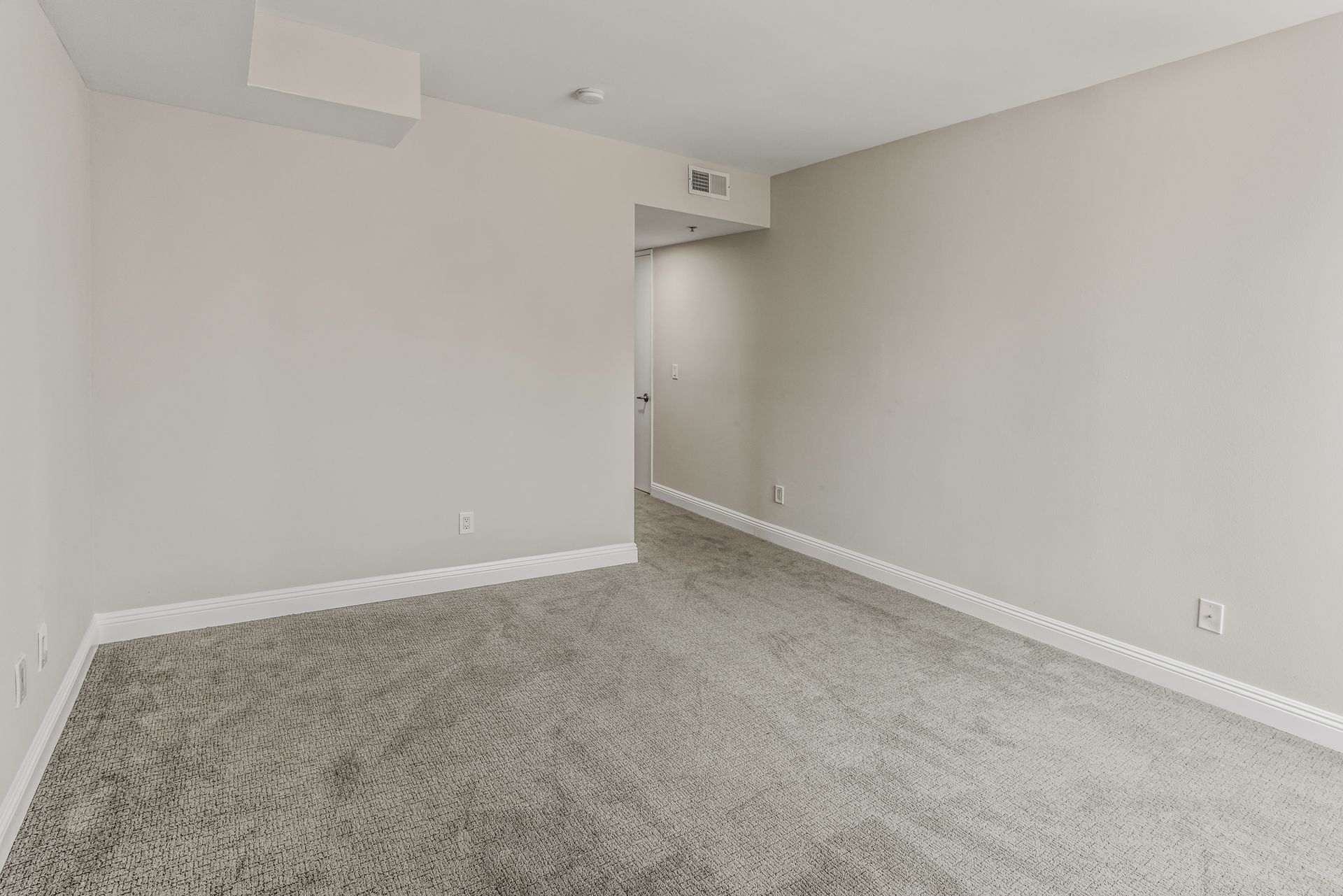 Empty carpeted room with white walls and a doorway