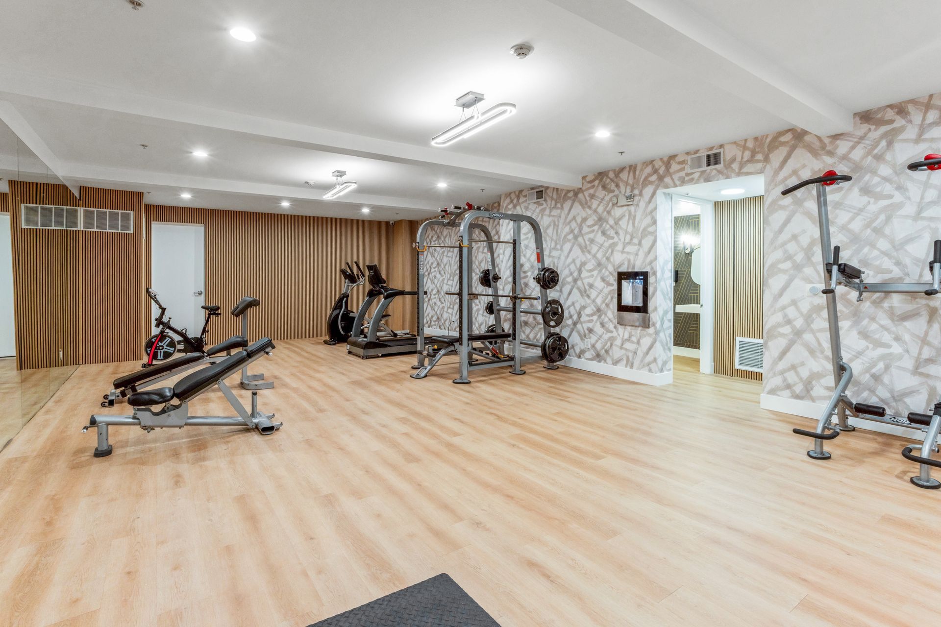 Spacious home gym with exercise equipment, mirrors, and light wood floors