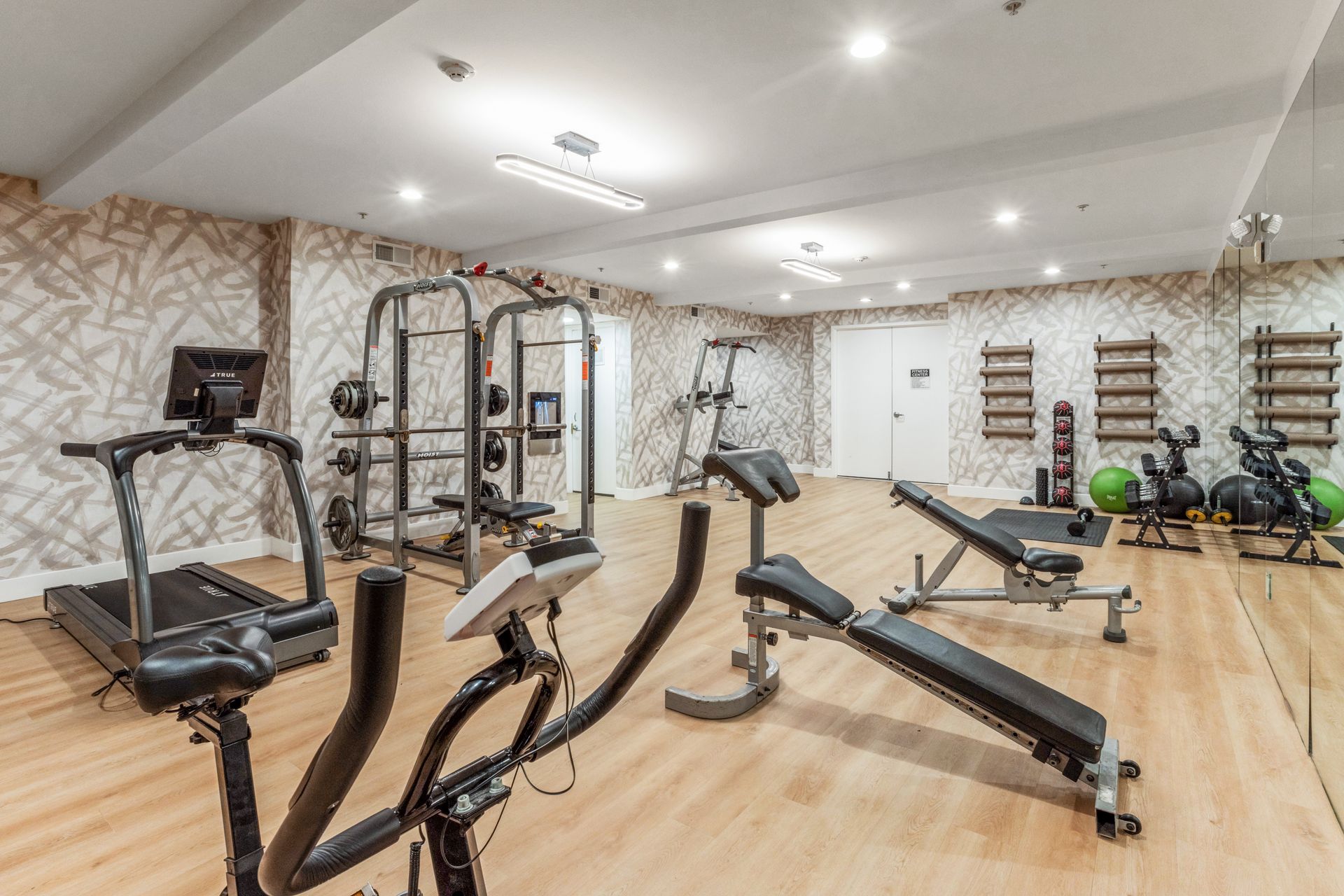 Modern gym with treadmills, weight machines, and exercise bikes in a bright room