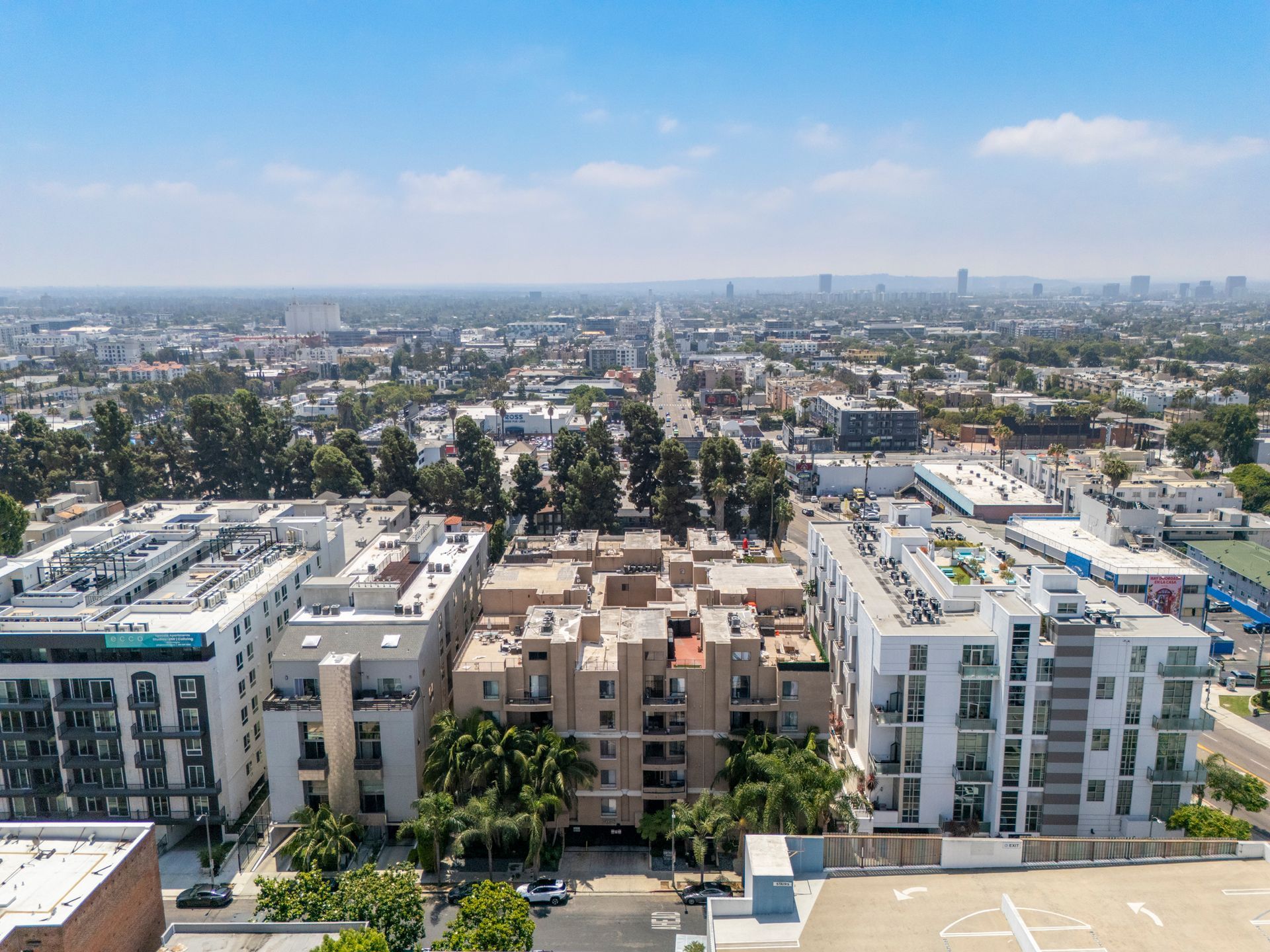 Wide cityscape from rooftop, with modern apartment buildings in the foreground and a hazy skyline beyond.