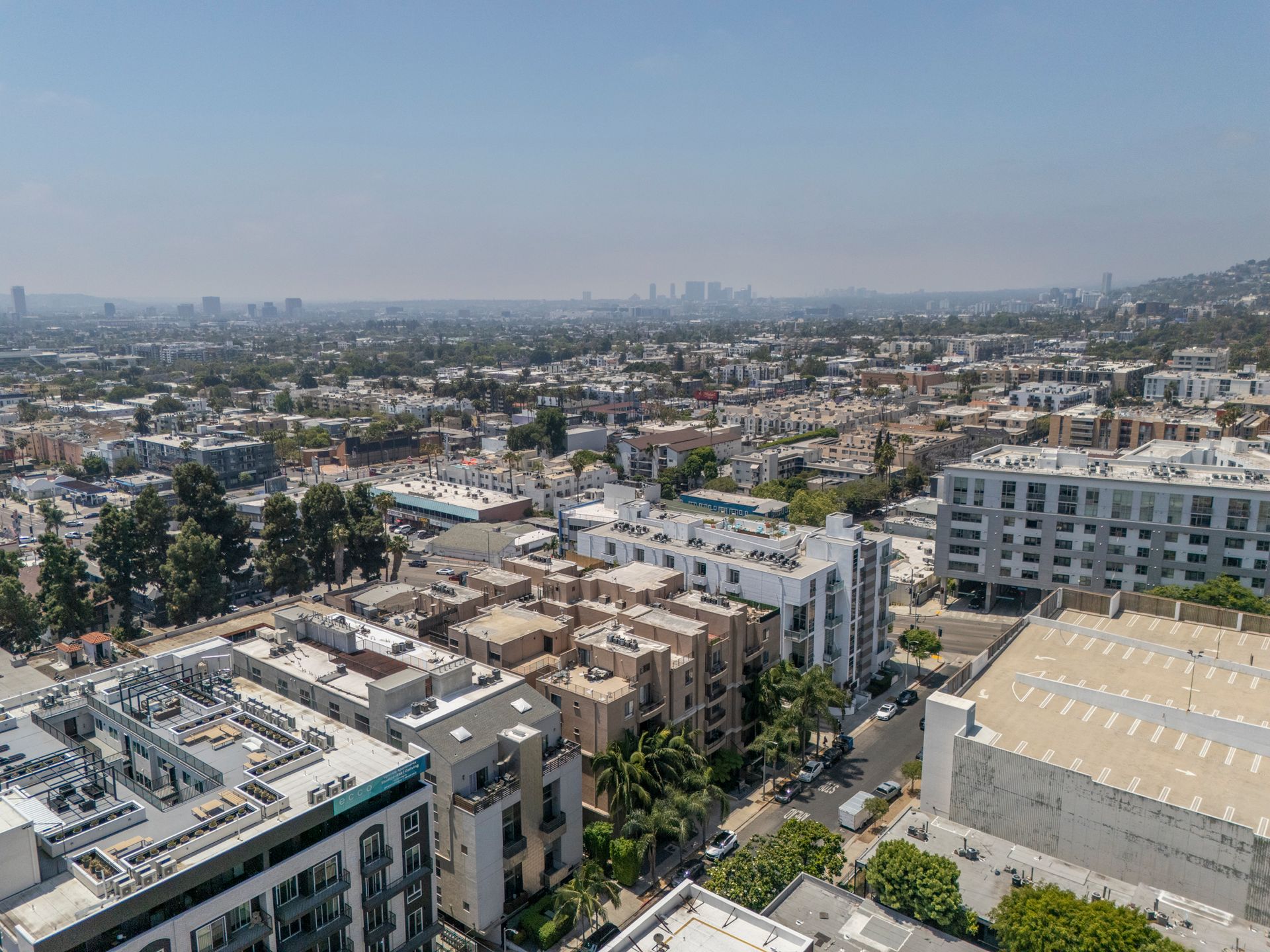 Aerial view of a dense cityscape with low-rise buildings and a hazy skyline in the distance