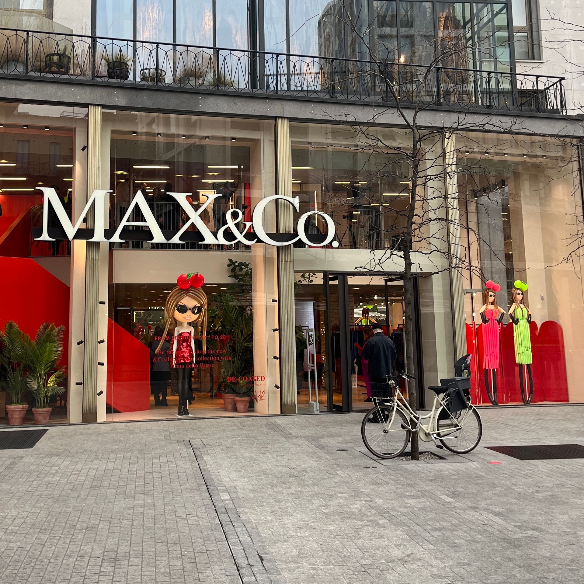 A bicycle is parked in front of a max & co store