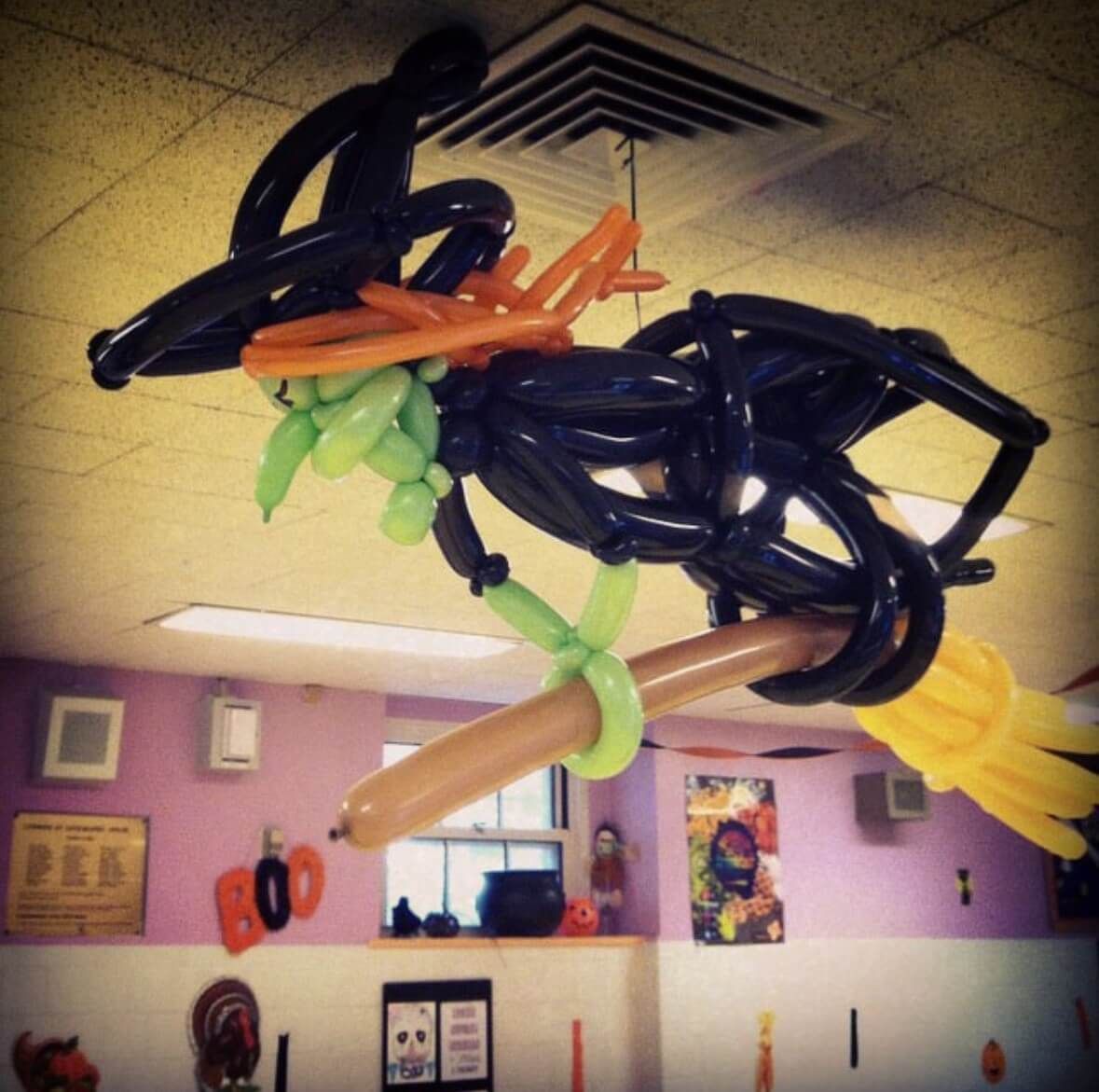 A witch made out of balloons is flying on a broom