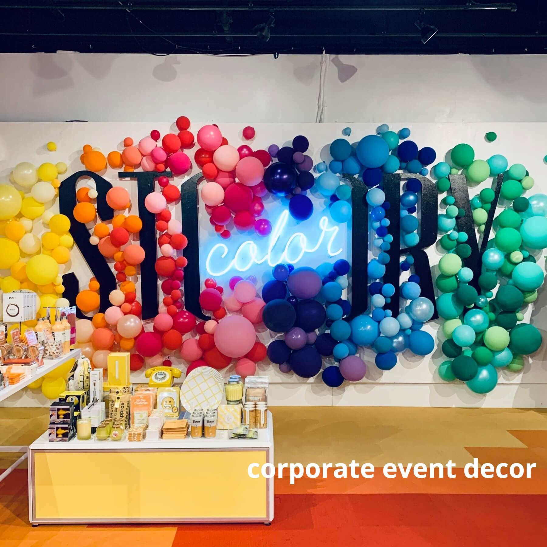 A wall with balloons and a neon sign that says color story