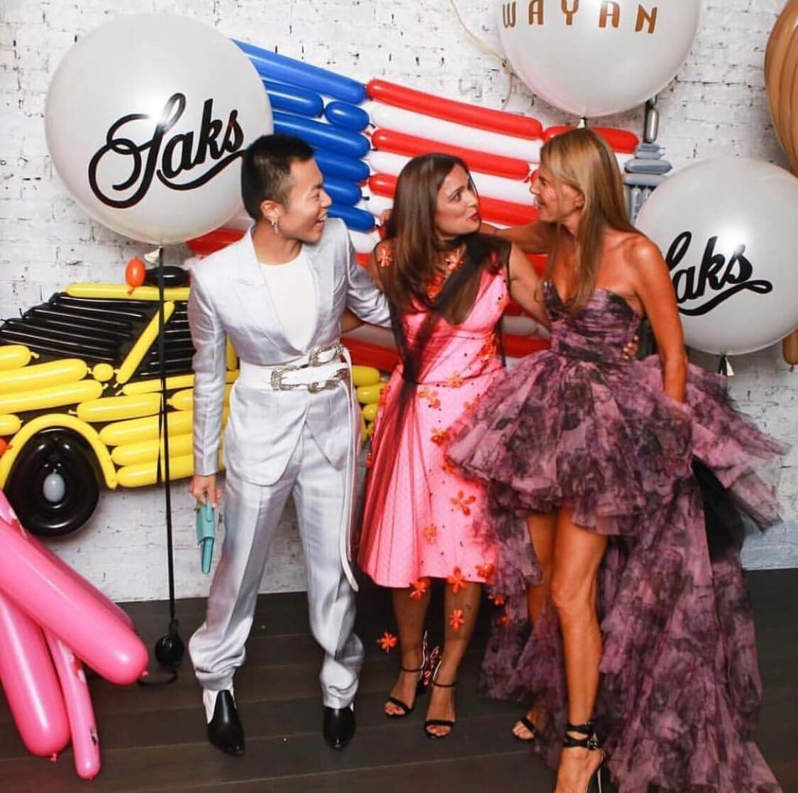 A group of people standing in front of balloons that say saks