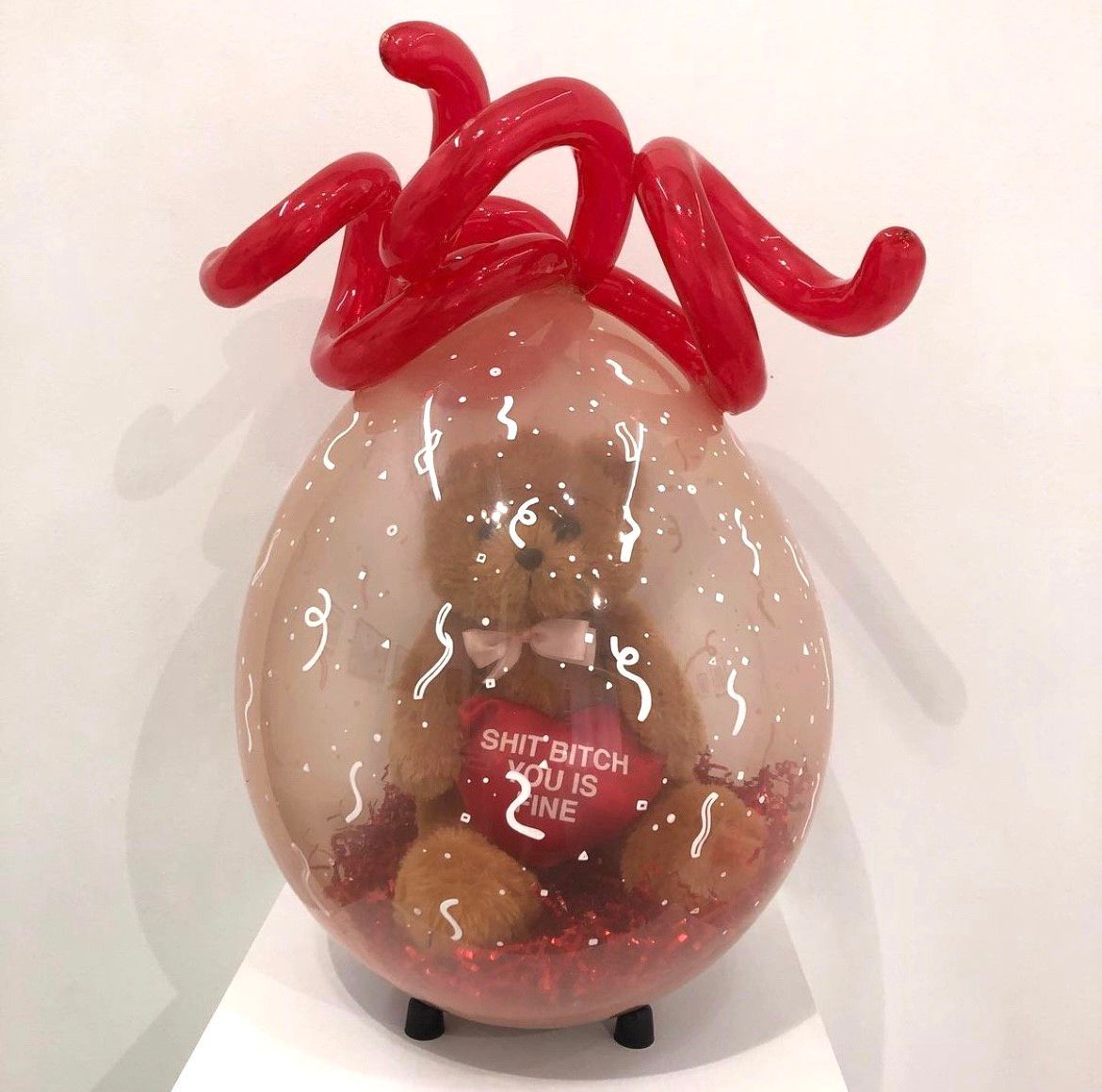 A stuffed teddy bear in a heart shaped balloon