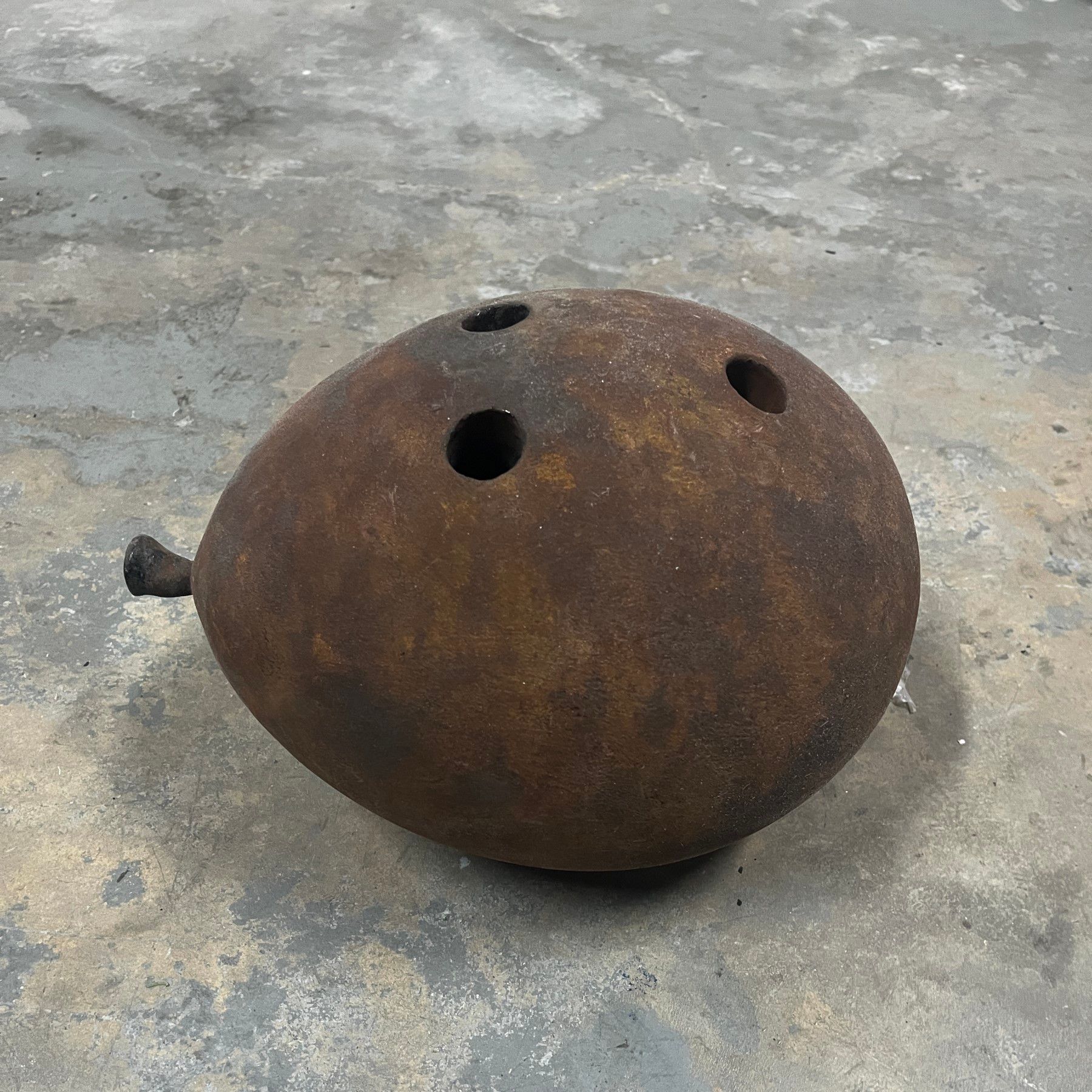 A rusty bowling ball with three holes in it