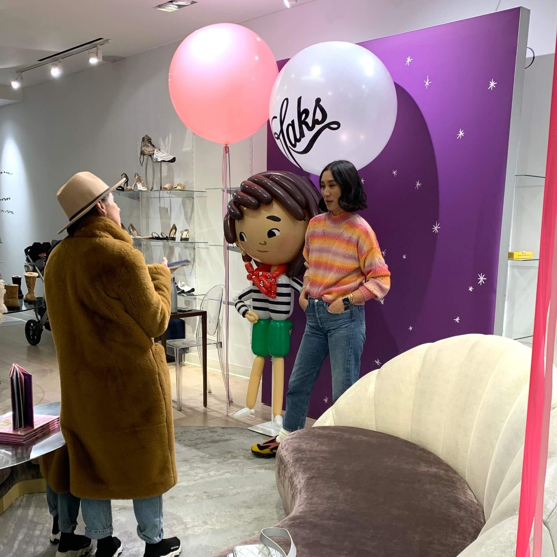 A woman is standing next to a balloon that says taks on it