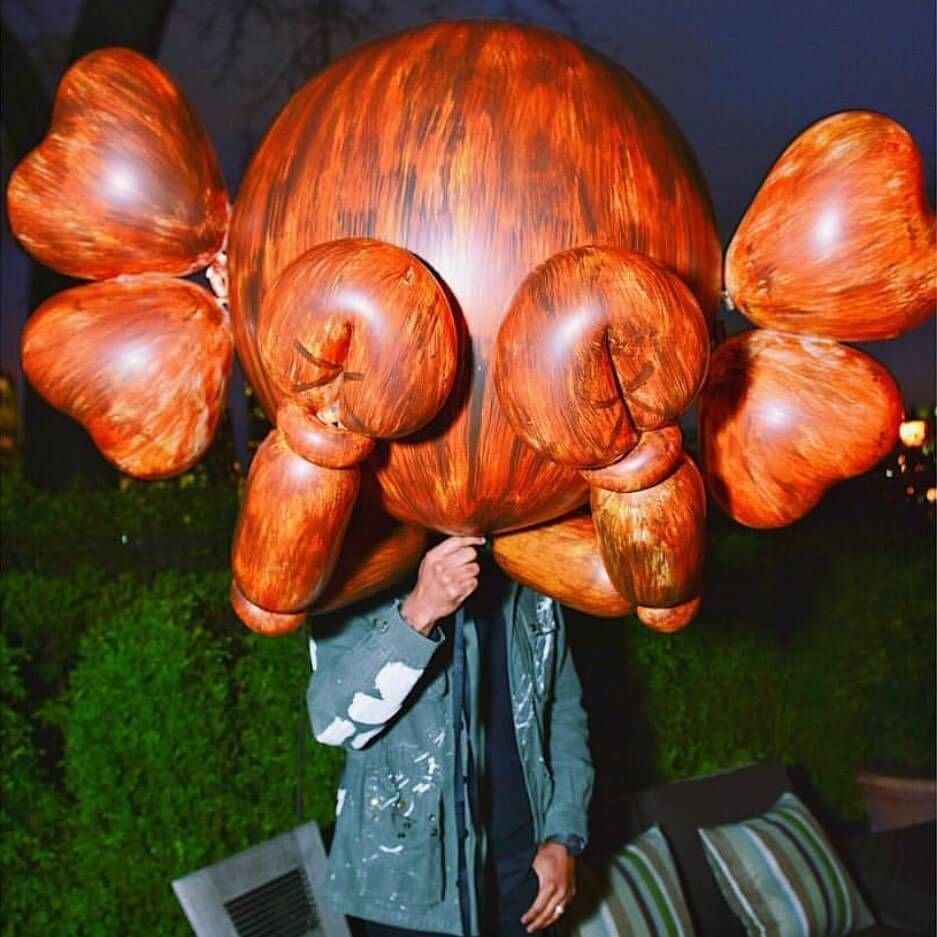 A man is holding a large wooden sculpture in front of his face
