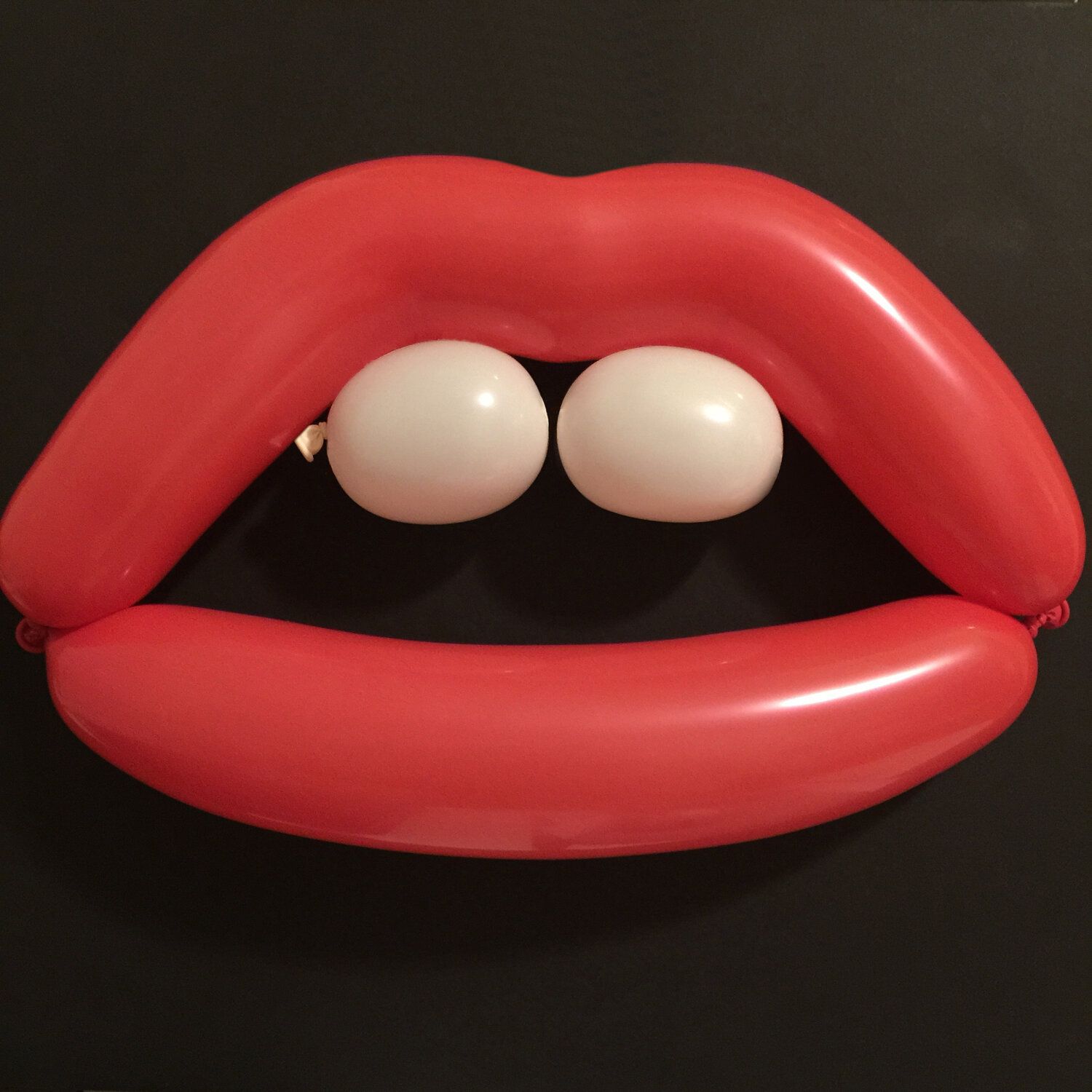 Red balloon lips with two white balloon teeth.