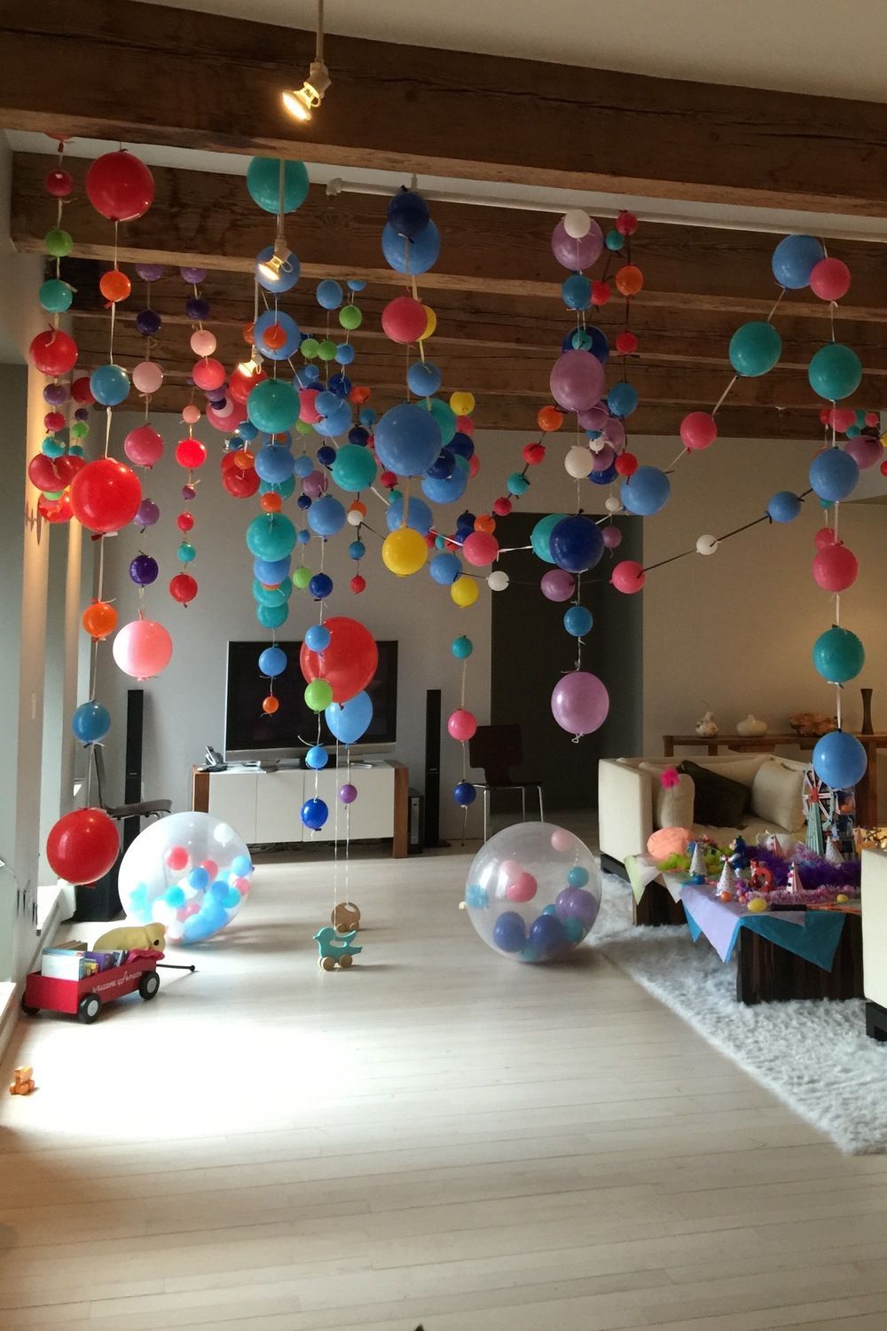 Room decorated with colorful balloons hanging from the ceiling; celebration or party.