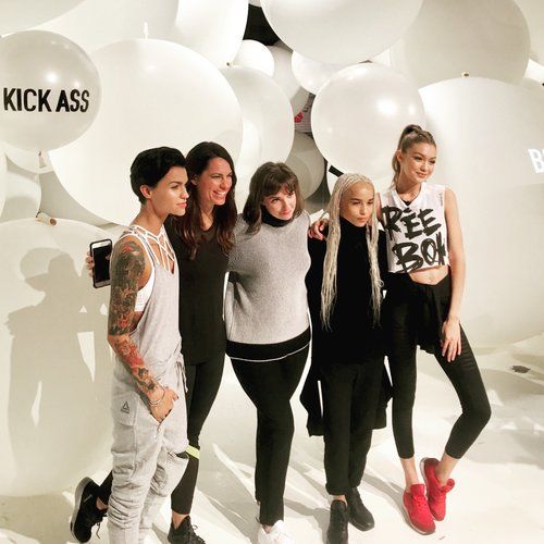 Group of people pose in front of white balloons, some with 