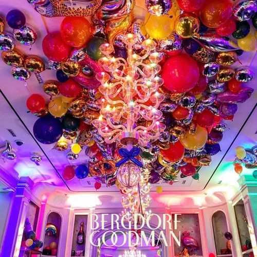 Colorful balloons and chandelier decorate a Bergdorf Goodman storefront ceiling.