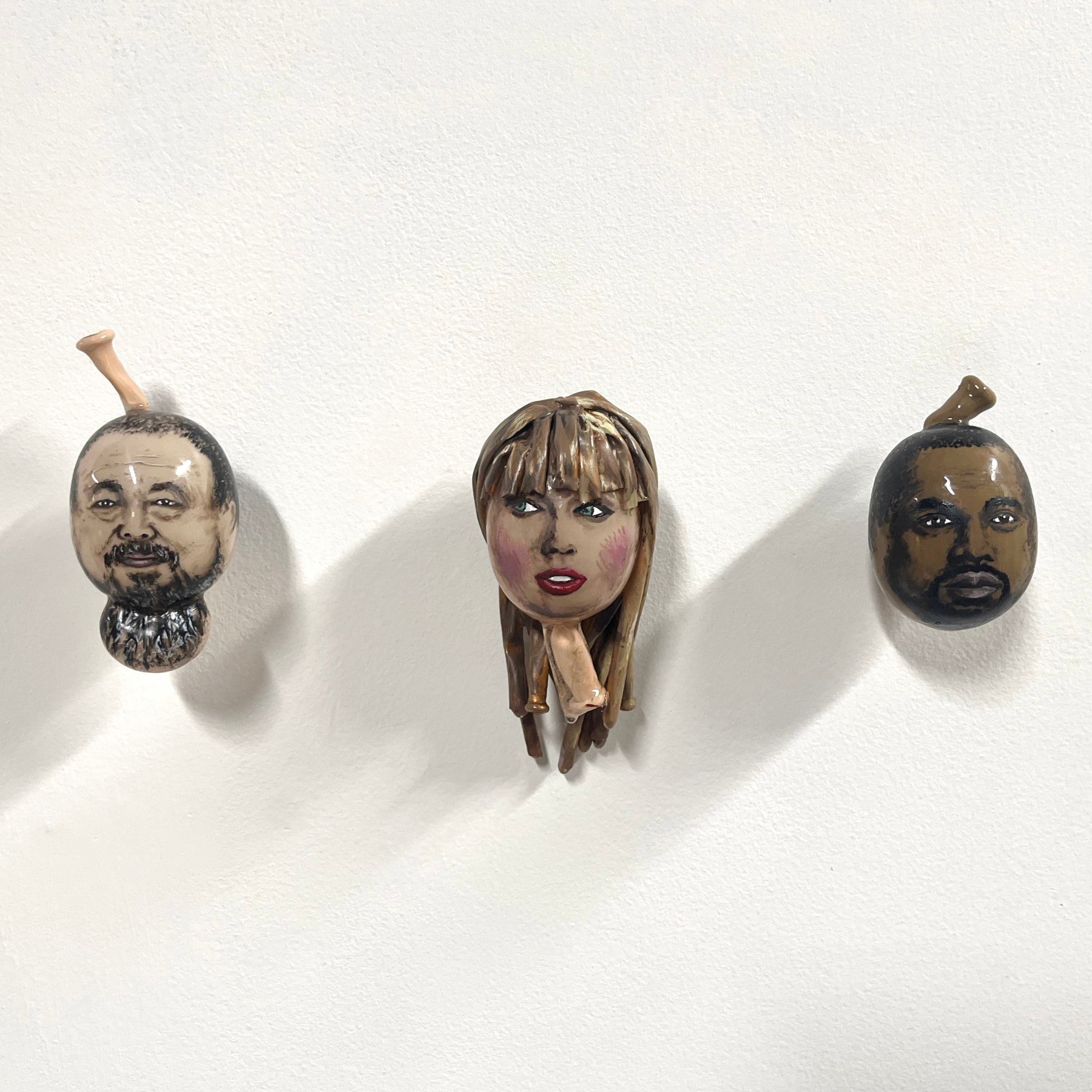 A man a woman and a man with a beard are hanging on a white wall