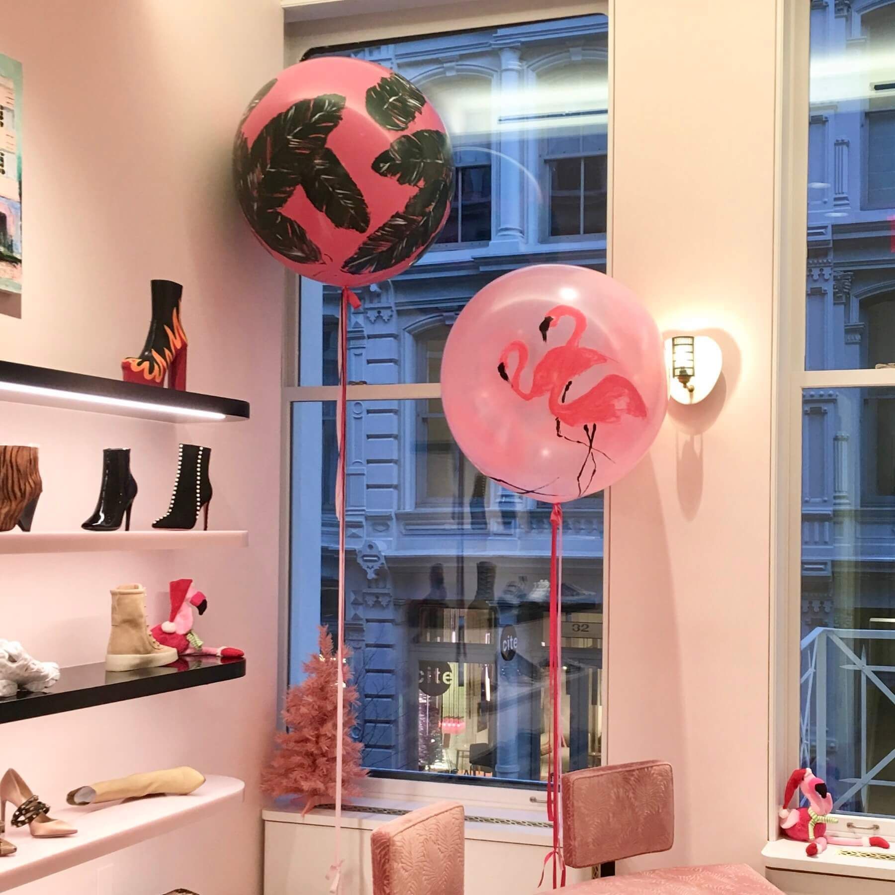 Two pink balloons with designs, near a window in a shoe store.