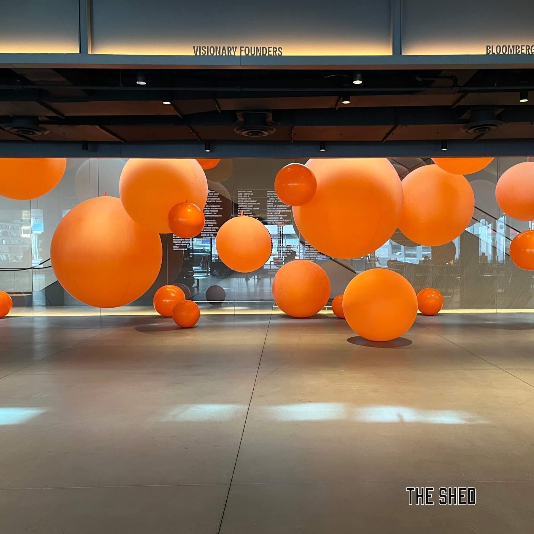 Large orange spheres float indoors; The Shed.