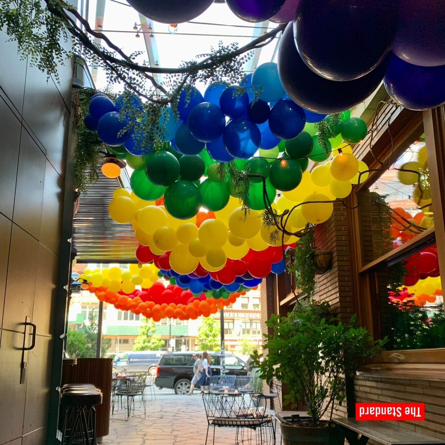 A rainbow of balloons decorates an outdoor dining space.