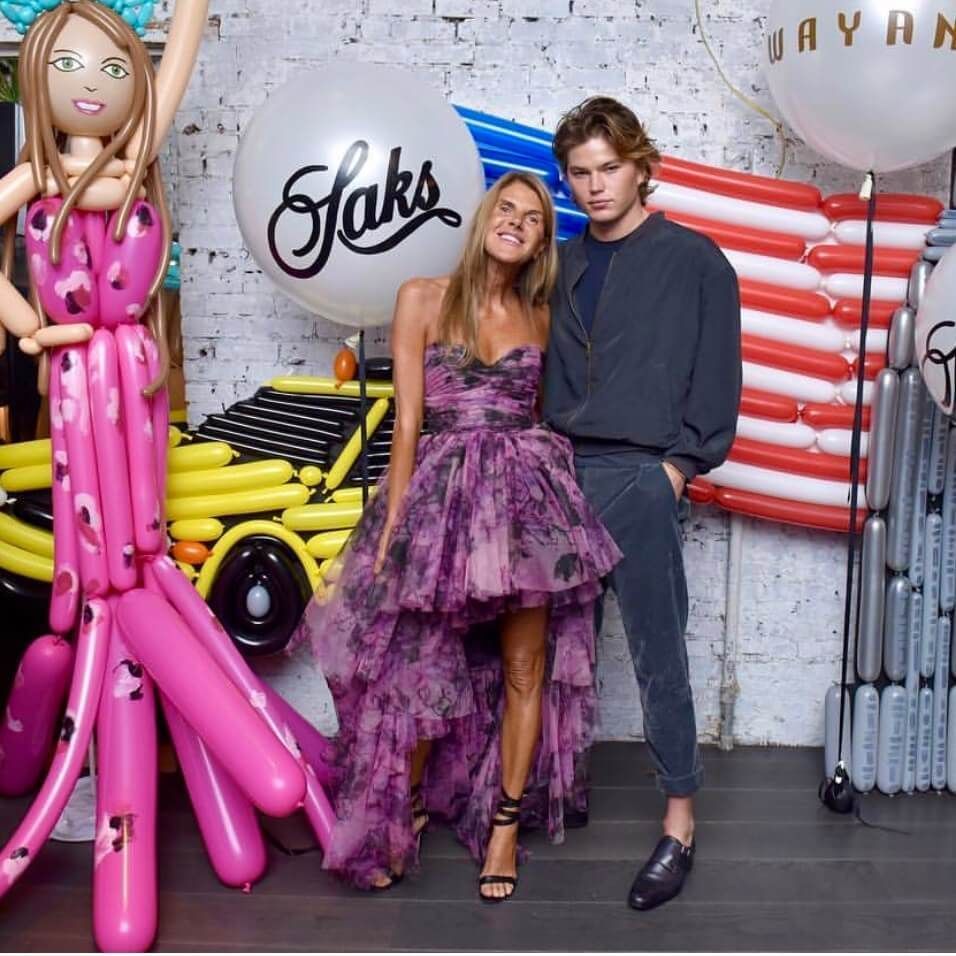 Woman in purple dress with man, balloons reading 
