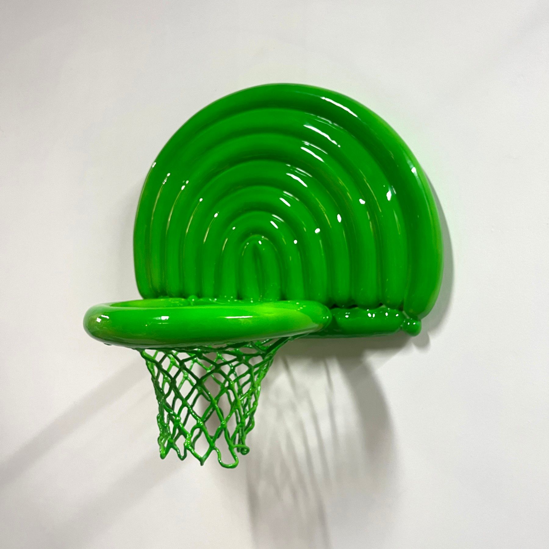 A green basketball hoop is hanging on a white wall.