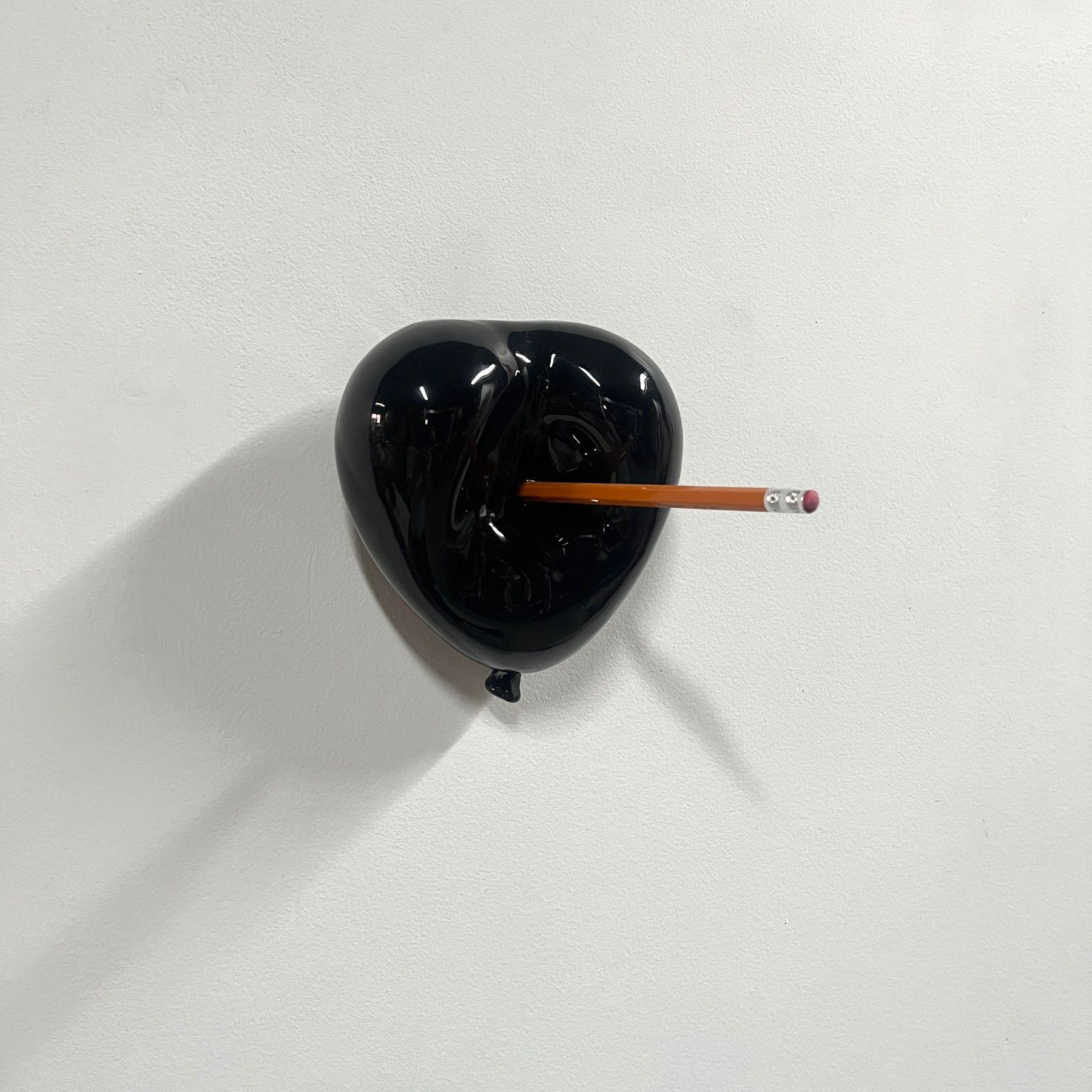 A black heart shaped object with a pencil sticking out of it.