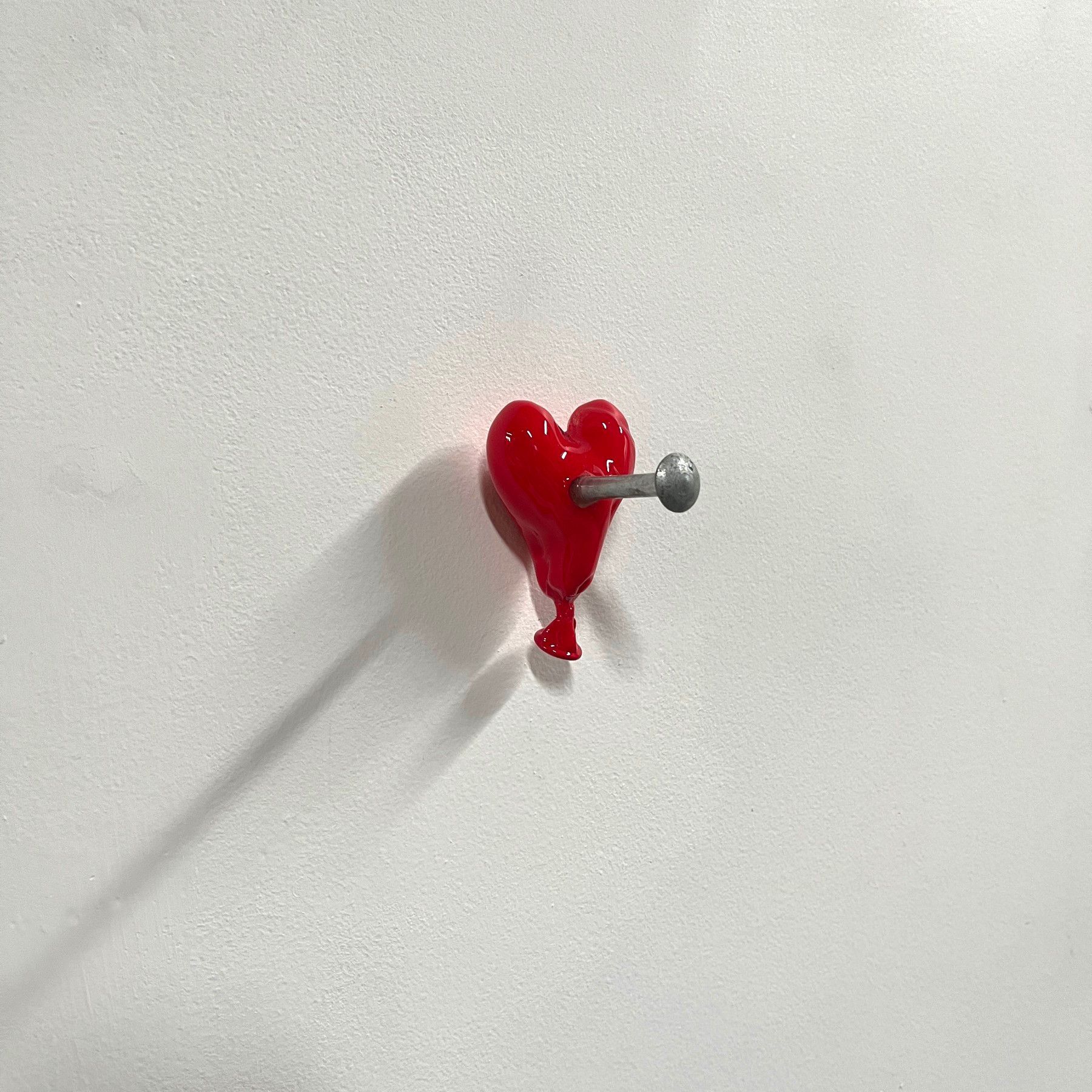 A red heart shaped hook on a white wall