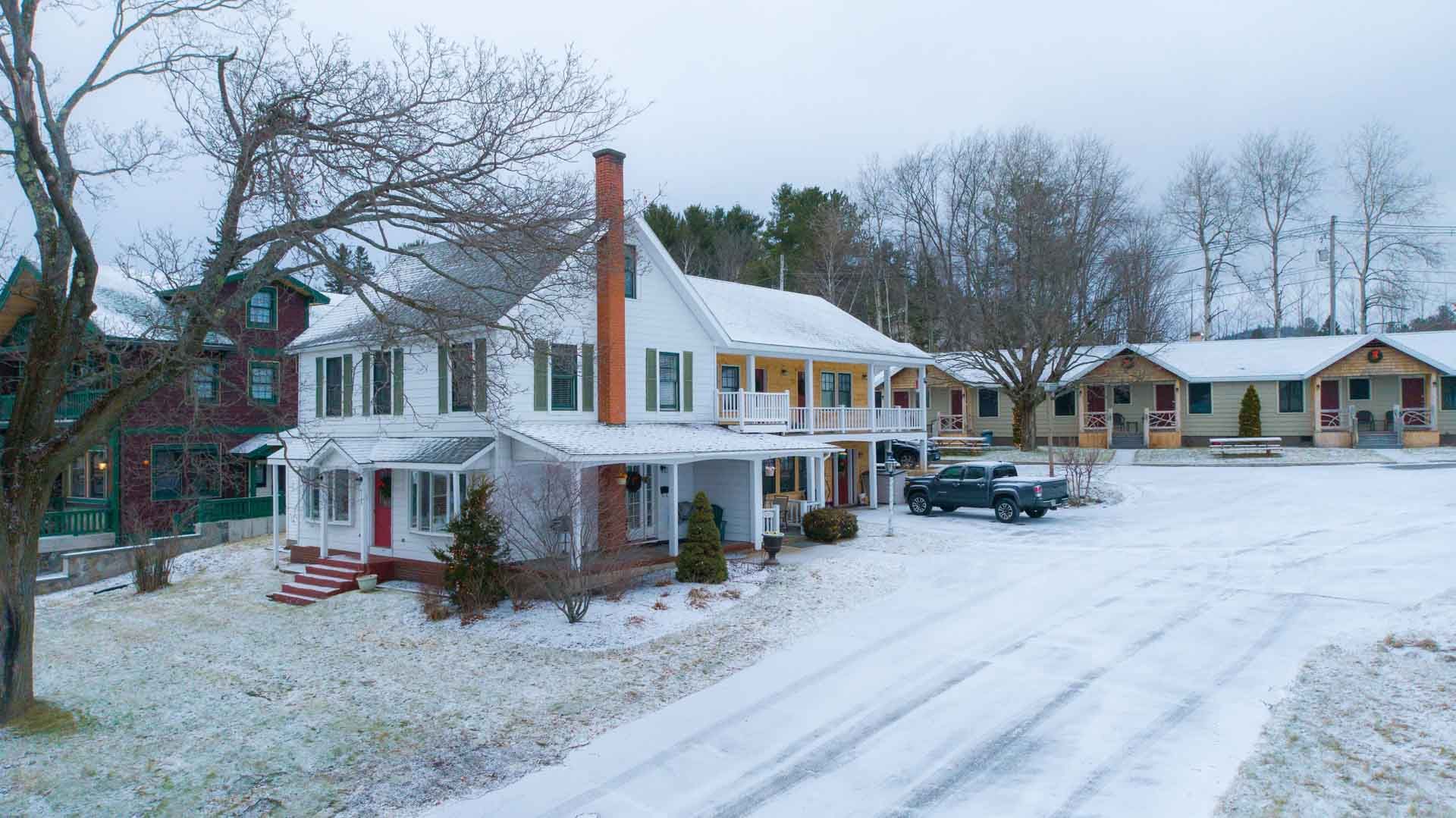 A large white house is sitting in the middle of a snow covered field.