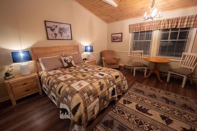 A bedroom with a bed, chair, table, and rug.