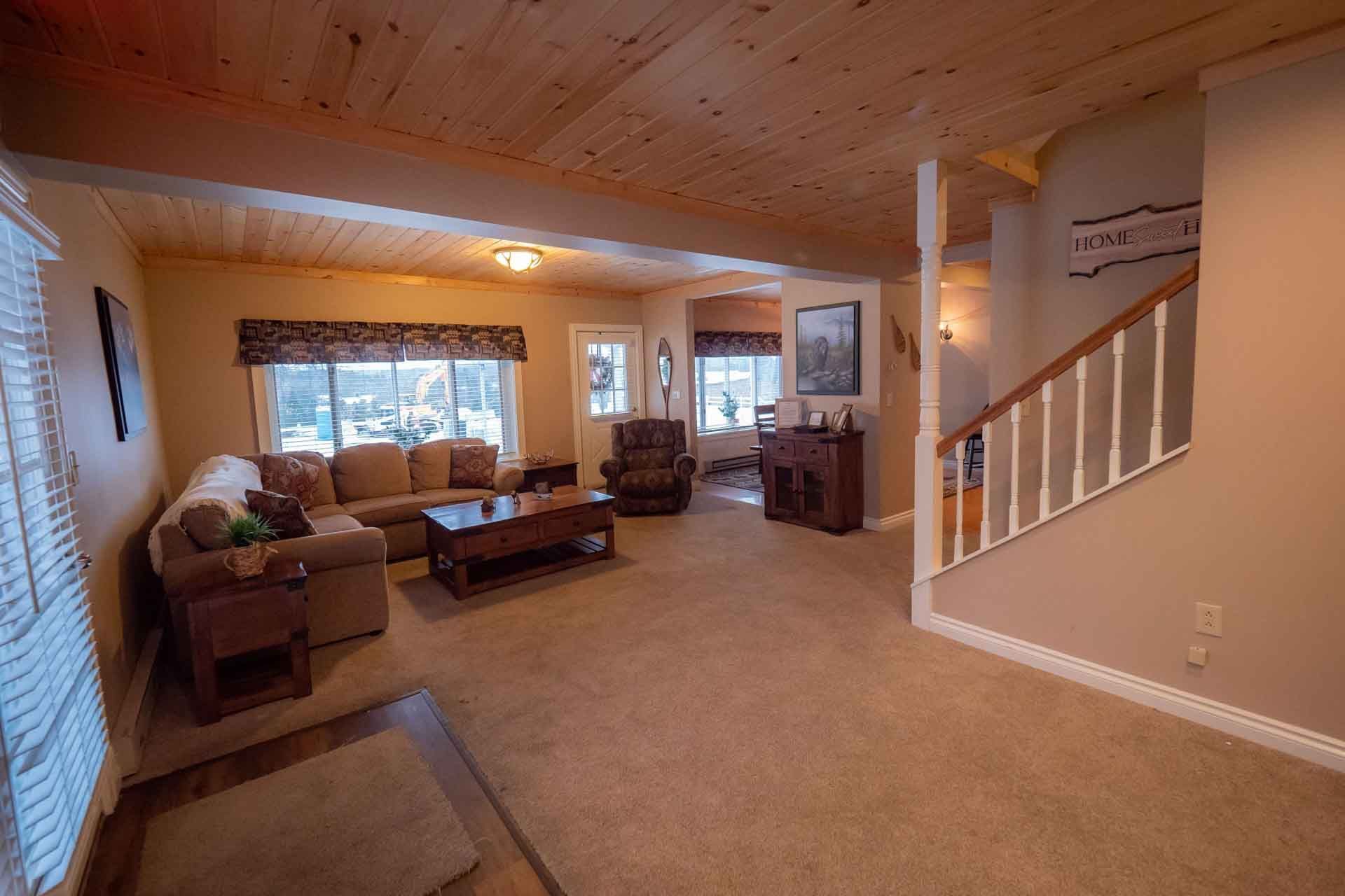 A living room with a couch, chair, coffee table and stairs.
