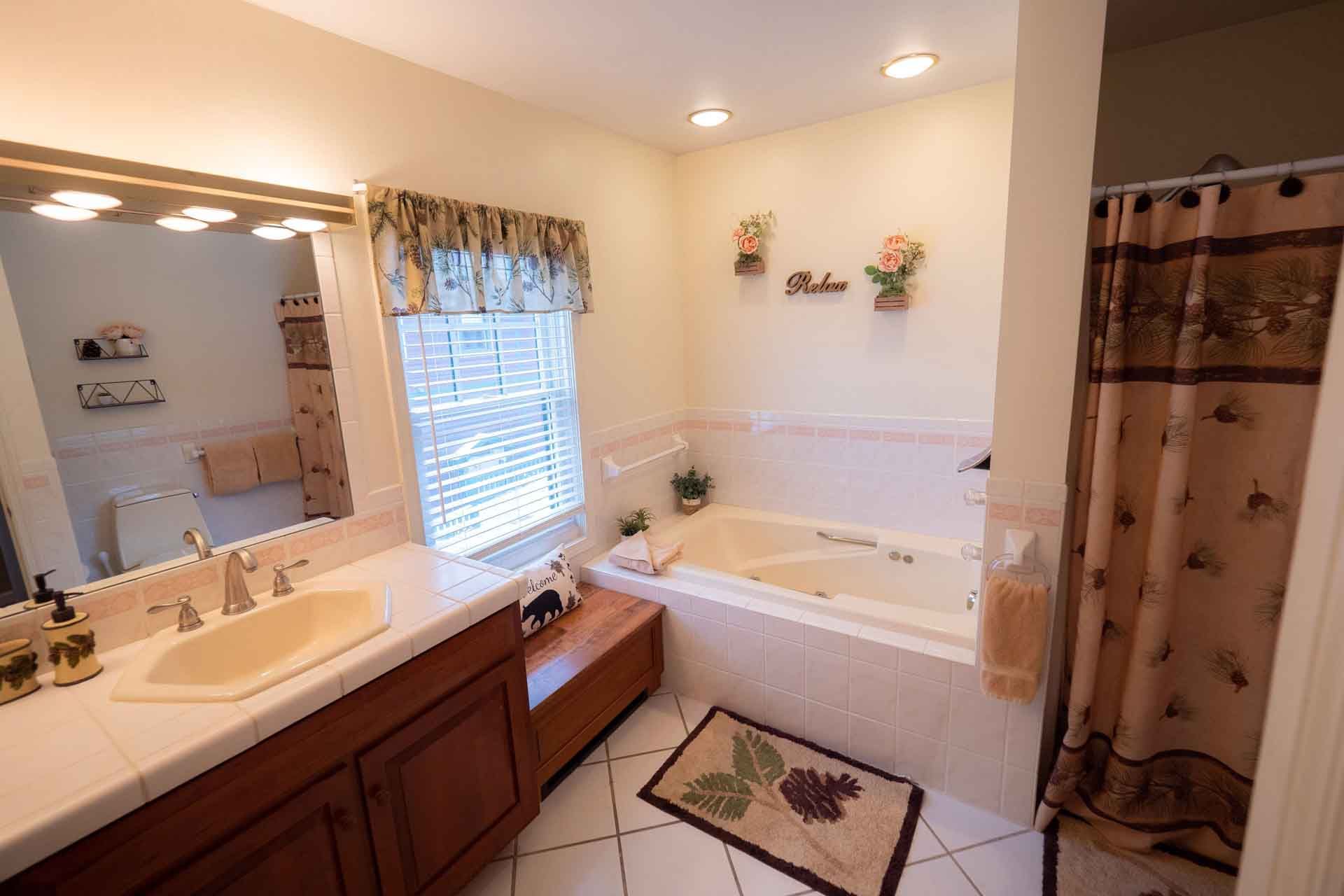 A bathroom with a tub, sink, and mirror.