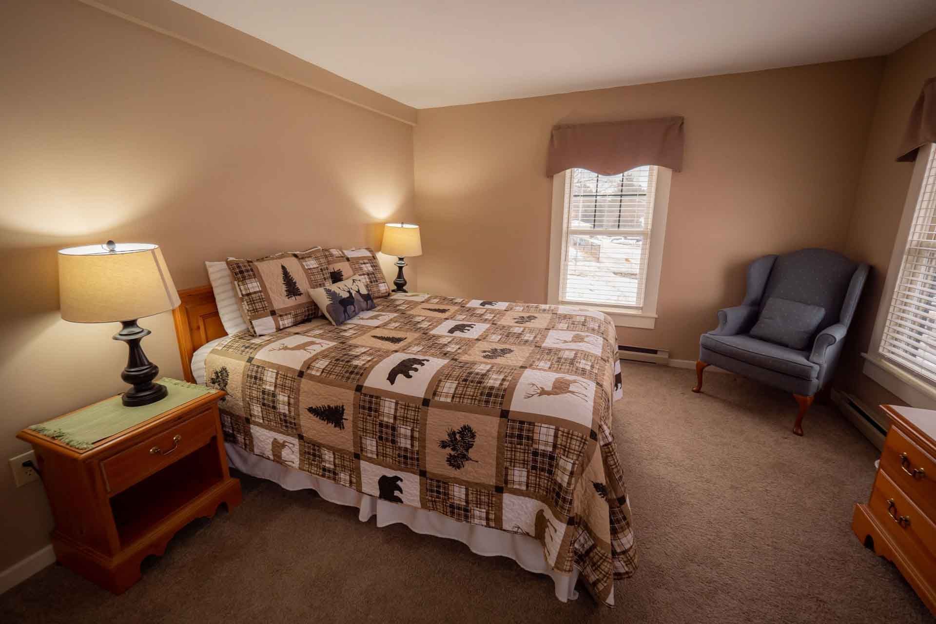 A bedroom with a bed, nightstand, chair and window.
