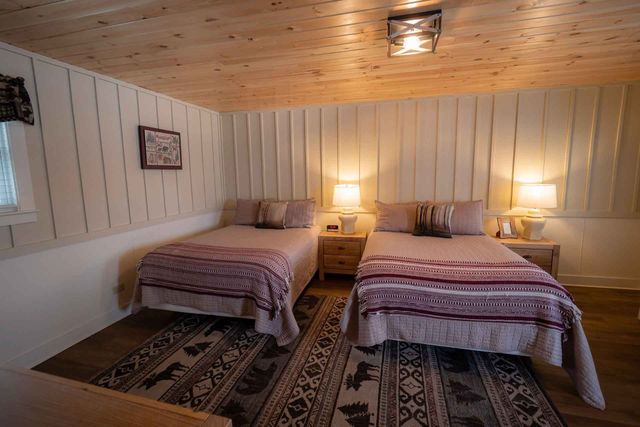 A bedroom with two beds and a rug.