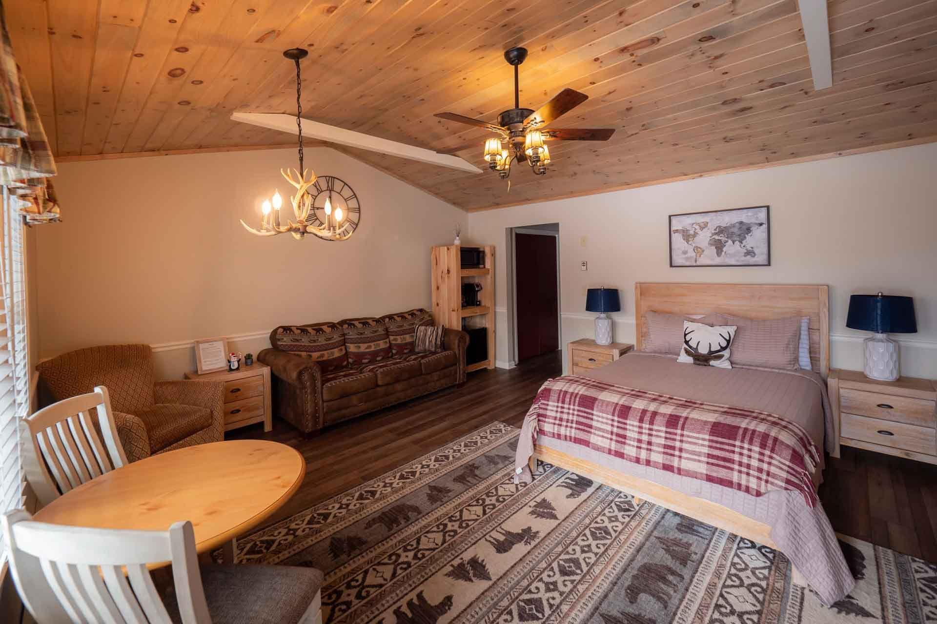 A bedroom with a bed, couch, table, and chairs.