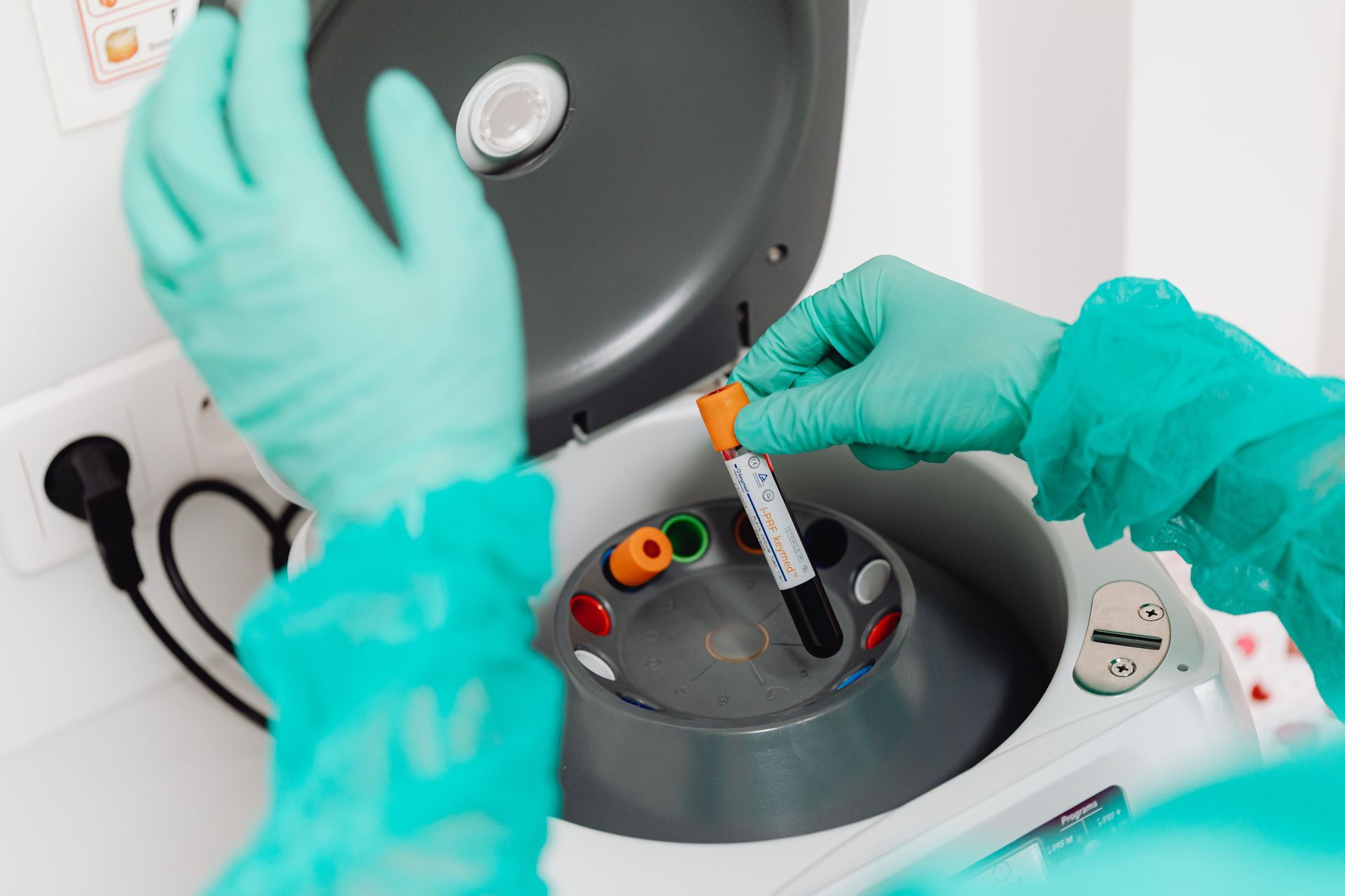 Gloved hands holding a test tube in a clinical lab