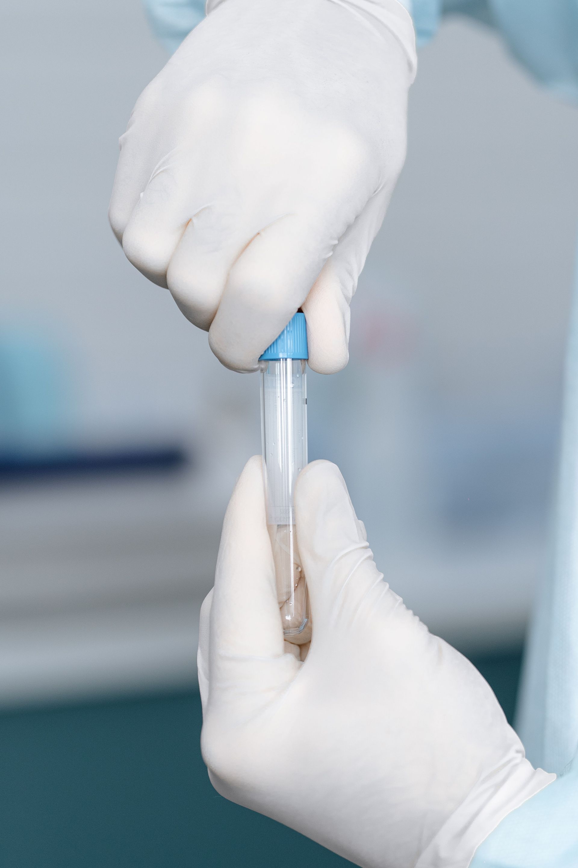 Gloved hands holding a test tube in a clinical lab