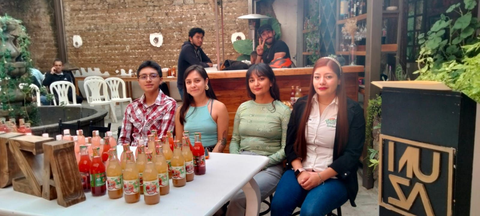 Un grupo de personas está sentado en una mesa con botellas de refresco encima.