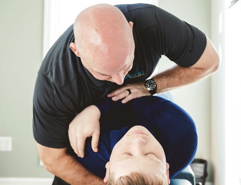 A chiropractor adjusts a person lying on their back.