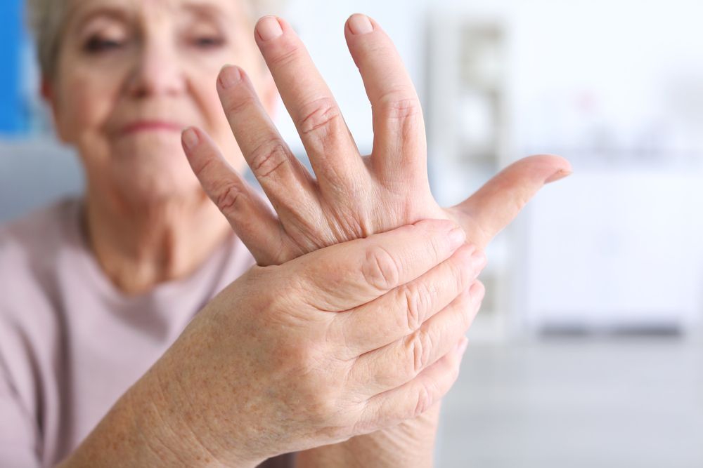 Elderly person holding their hand in pain.