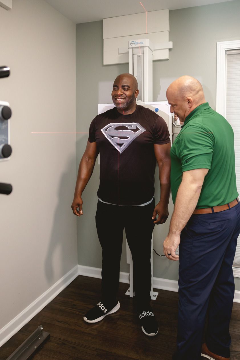 A bald chiropractor adjusts a patient on a table.