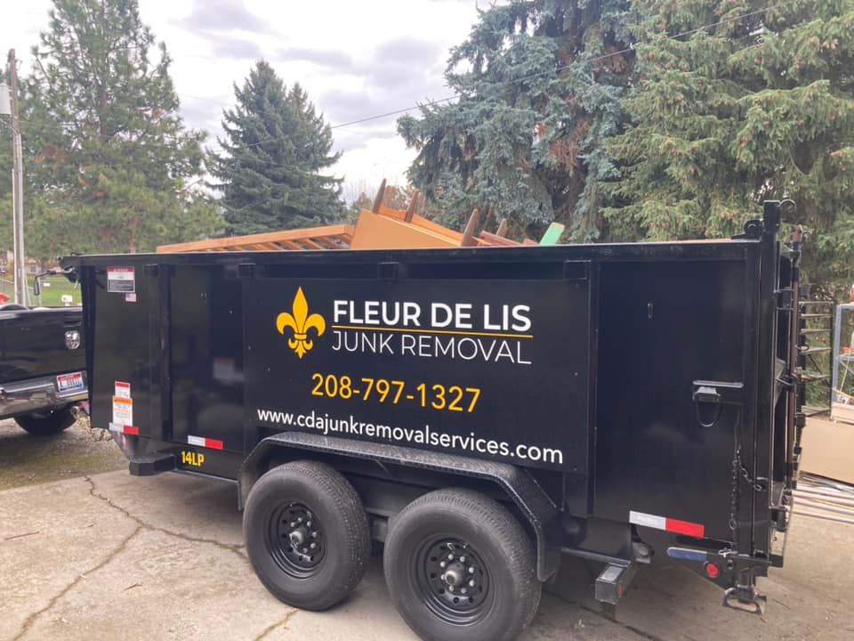 a fleur de lis junk removal trailer is parked in a driveway next to a truck .