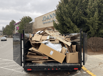 a dumpster filled with cardboard boxes is parked in front of a store .