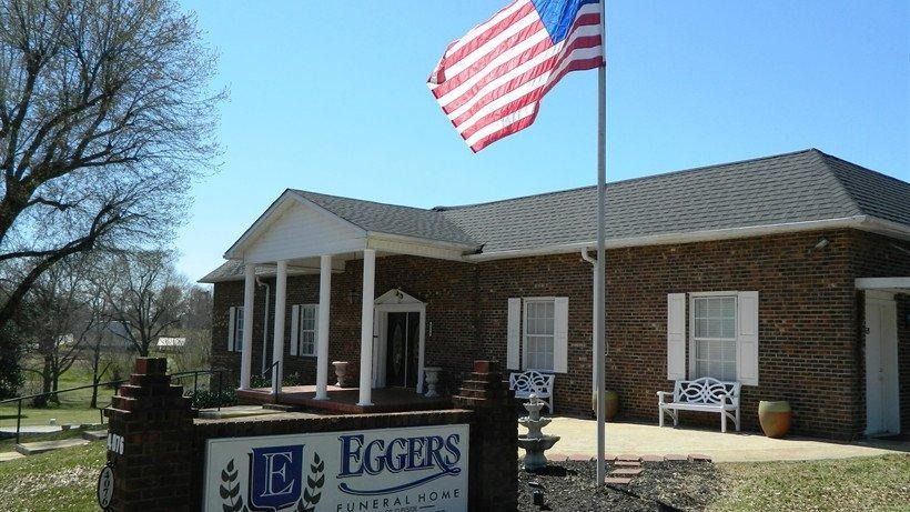 Eggers building with white columns and a U.S. flag flying outside under a clear sky