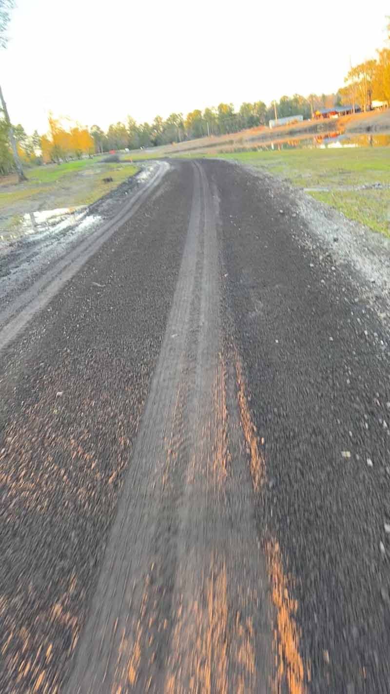 Freshly laid gravel road curving through a rural landscape at sunset