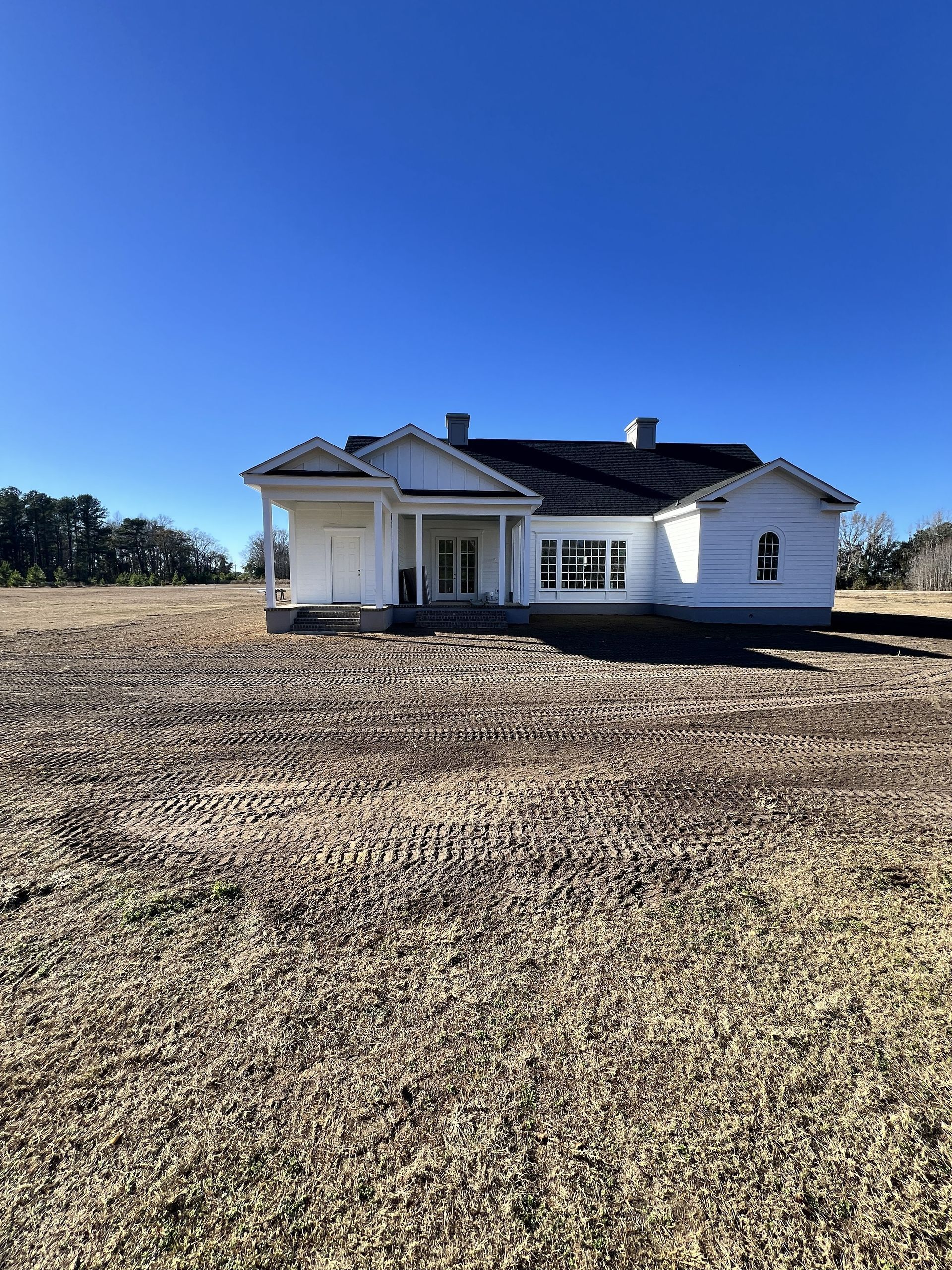 Small white house in a dry grassy field under a bright blue sky