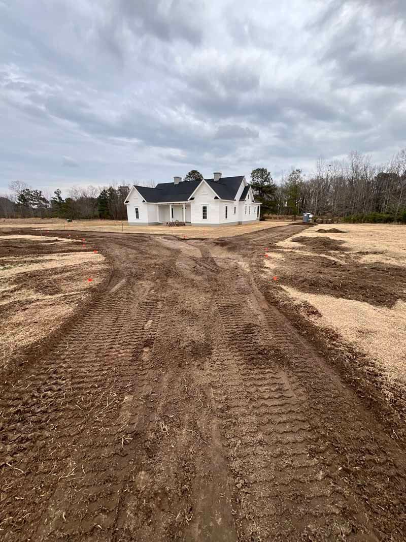 White house at end of muddy dirt road under cloudy sky