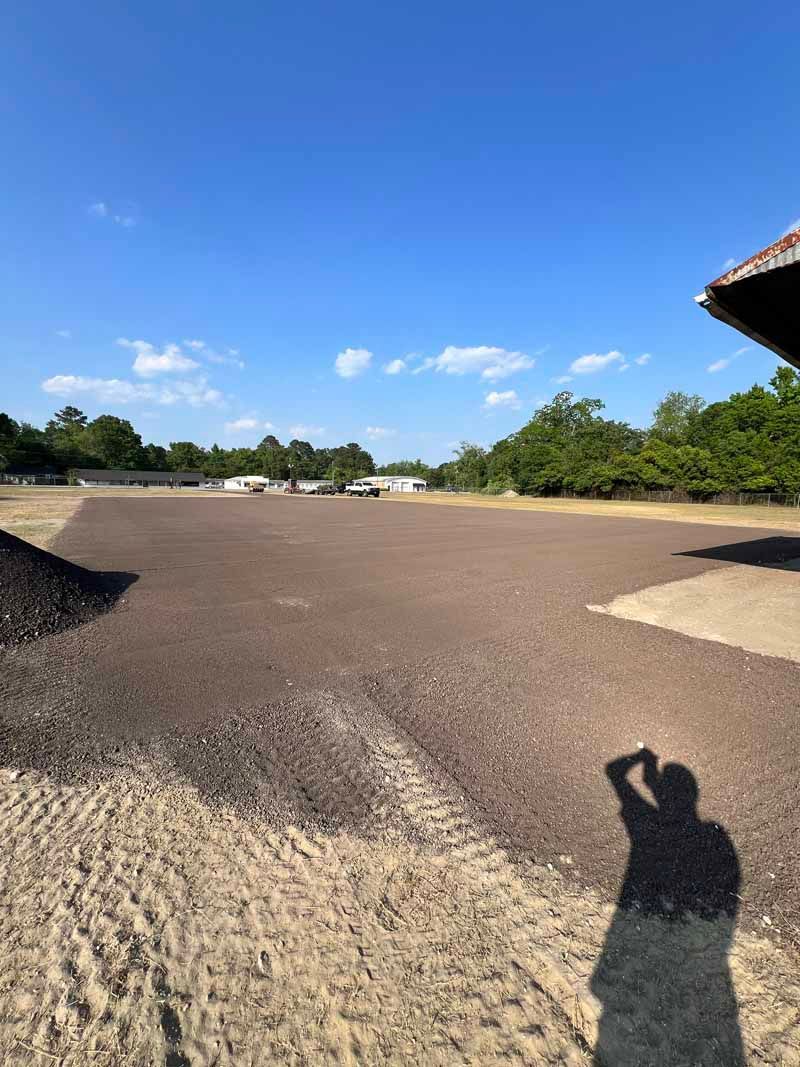 Rooftop with gravel surface under a blue sky, with a person’s shadow in the foreground.