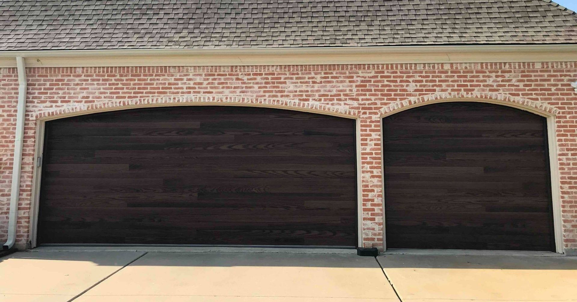 There are two garage doors on the side of a brick building.