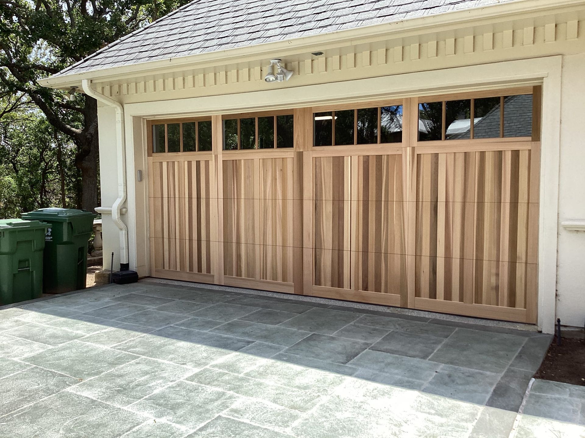 A large wooden garage door is sitting in front of a white house.