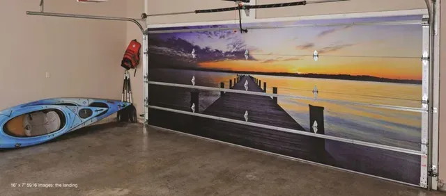 A garage with a painting on the garage door and a kayak.