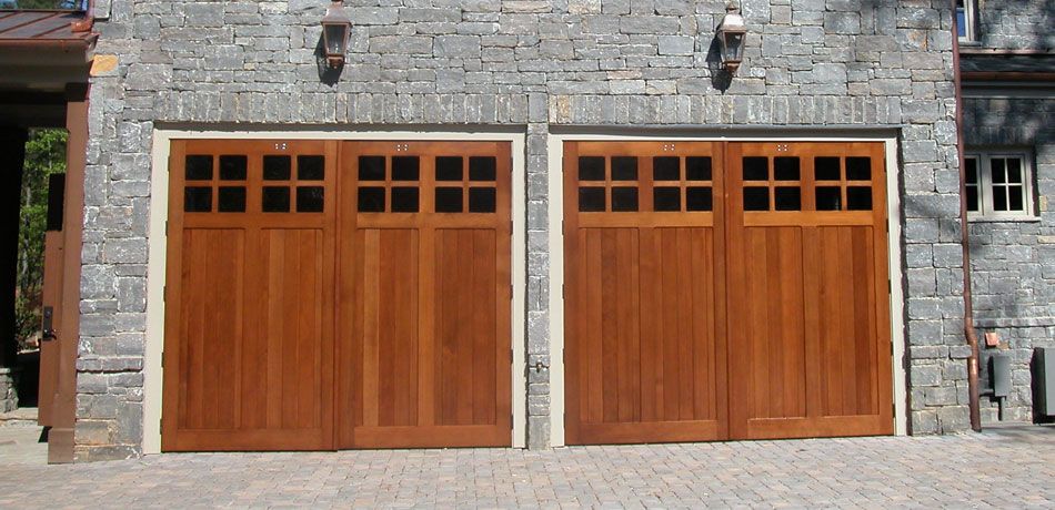 A pair of wooden garage doors on a brick building.